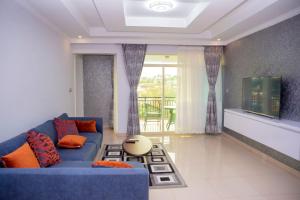 sala de estar con sofá azul y TV en Grazia Apartments, en Kigali
