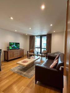 uma sala de estar com um sofá e uma televisão em New Beautiful Lux Apartment em Londres