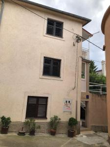 a white building with two windows and potted plants at Old city core in Senj