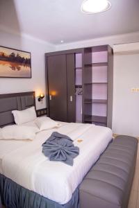 een slaapkamer met een groot wit bed met een blauw shirt erop bij Grazia Apartments in Kigali