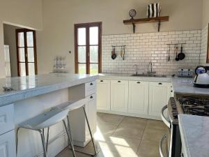 a kitchen with white cabinets and a counter with stools at Rancho Contento Polo House in Cañuelas