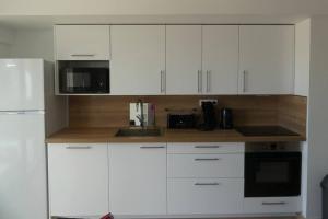 a kitchen with white cabinets and a microwave at La belle vie F4 bord de plage avec jardin in Calcatoggio
