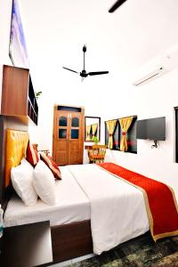 um quarto com uma cama grande com lençóis brancos e almofadas vermelhas em The Beach Cottage Kappad em Calecute