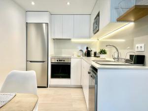 a white kitchen with a sink and a refrigerator at Llagut in L'Escala