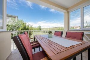 a wooden table and chairs on a balcony with a view at Apartmani Ana & Milo in Lopar