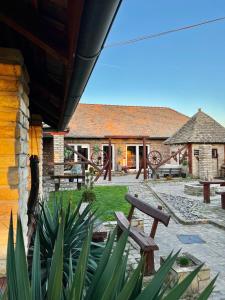 a patio with benches and tables and a building at Salaš kod Bobana in Bač