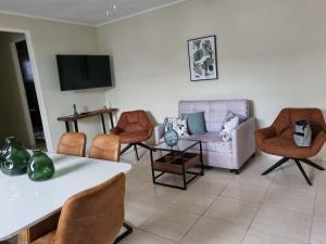 sala de estar con sillas, sofá y TV en Angola Apartment "A", en Willemstad