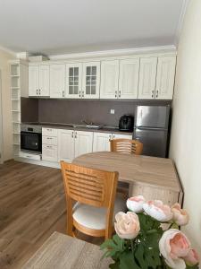 a kitchen with white cabinets and a table and chairs at South Beach Apartment at Valencia Gardens in Nesebar