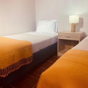 a bedroom with two beds and a night stand with a lamp at CASA TAMBO in San Pedro de Atacama
