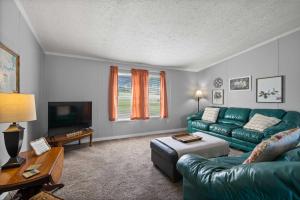 sala de estar con sofá verde y TV en Eatonton Home with Dock and Lake Sinclair Views!, en Eatonton