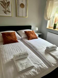 2 camas en una habitación con sábanas blancas y toallas en Osada Gęsin, en Zabór