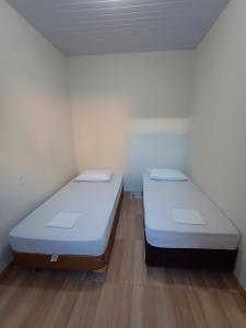 two beds in a small room with wooden floors at AP 2 quartos e cozinha de uso exclusivo in Sorriso