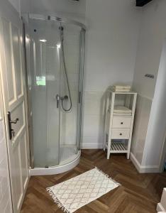 La salle de bains est pourvue d'une douche et d'un tapis blanc. dans l'établissement Osada Gęsin, à Zabór