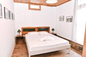 a bedroom with a white bed with a wooden headboard at Barreira Beachfront Room 1 in Verga Kalamata