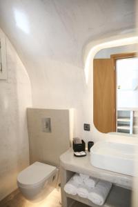a white bathroom with a sink and a toilet at Luxury Canava in Emporio