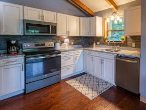 a kitchen with white cabinets and black appliances at Lakeside Mountain Oasis - 3 Bedroom Cabin with Outdoor Hot Tub in Topton