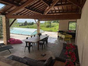 um pátio com uma mesa e cadeiras e uma piscina em Grande maison avec piscine em Senouillac