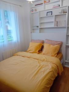 - un lit avec des draps et des oreillers jaunes dans une chambre dans l'établissement Maison Gradina - Séjour à Annecy entre lac et montagne, à Metz-Tessy
