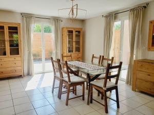 una sala da pranzo con tavolo in vetro e sedie di Maison Gradina - Séjour à Annecy entre lac et montagne a Metz-Tessy