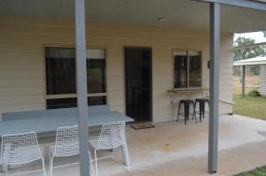 eine Terrasse mit Stühlen und einem Tisch an einem Haus in der Unterkunft Blackbutt The Shack at Gilinlea in Benarkin