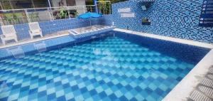 a blue tile swimming pool with two chairs and an umbrella at Hotel spa la buena vida in Fusagasuga