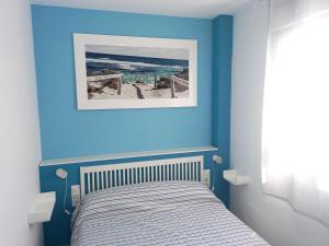 a bedroom with a bed with a blue wall at Casa Malakita with private seaview roof terrace in Conil de la Frontera +22 photos
