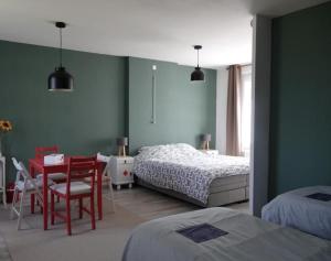 a bedroom with two beds and a desk and a table at Les hirondelles du moulin in Sassay