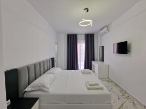a white bedroom with a large bed with white sheets at Vila Klari in Ksamil