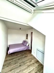 Un dormitorio con una cama morada en una habitación blanca. en Charmant T2 à Aix-les-bains !, en Aix-les-Bains