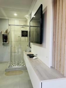 a bathroom with a shower and a television on the wall at Executive Galaxy Guest House Nkowankowa Extension 2 in Tzaneen +22 photos