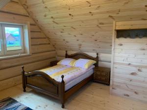 a bedroom with a bed in a log cabin at Zagroda na Borach - Domek in Jabłonka