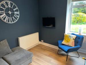 a living room with a couch and a clock on the wall at James St Park 2 bed Gr Flr, sleeps 4 in Helensburgh