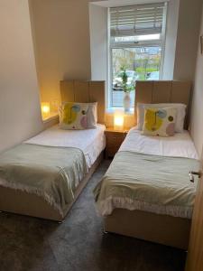 two beds in a room with a window at James St Park 2 bed Gr Flr, sleeps 4 in Helensburgh