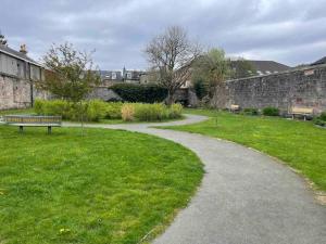 a path through a park with a bench in the grass at James St Park 2 bed Gr Flr, sleeps 4 in Helensburgh