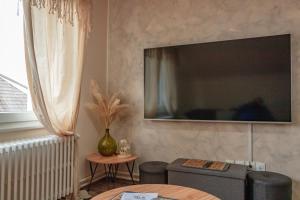 a living room with a large flat screen tv on the wall at Aux Portes de Colmar Évasion sur la route des Vins , à 5 minutes de Colmar in Ingersheim