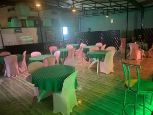 een kamer met groene en roze tafels en stoelen bij SKYLIGHT MOTEL Airport Road in Kigali