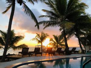 a swimming pool with palm trees and a sunset at Coral Cove Inn in Seine Bight Village