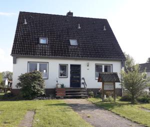 a white house with a black roof at CUXKieker - Moderne Ferienwohnung mit Pep in Cuxhaven-Sahlenburg, WLAN, Parkplatz und Gartenblick, nah am Nordseestrand und Wernerwald in Cuxhaven