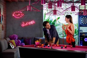 een man en een vrouw die naast een pooltafel staan bij MOXY Bandung in Bandung