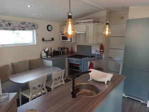 a kitchen with a sink and a counter with a table at Mobil-home FO 88 à VIAS in Vias