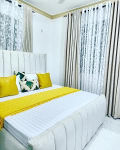 een slaapkamer met een groot wit bed met gele kussens bij Airbn b Mombasa Bamburi in Mombasa
