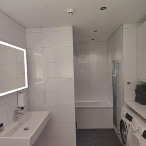 y baño blanco con lavabo y lavadora. en Esplanad Suites en Mariehamn