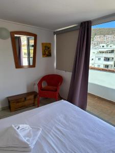 een slaapkamer met een bed, een rode stoel en een raam bij Bubu Beach 5 Ático in Los Cristianos