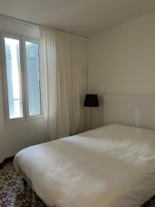 - une chambre avec un grand lit blanc et une fenêtre dans l'établissement La Suite 68 Bandol avec jardin et parking privatif, à Bandol