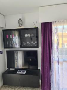 a living room with a tv and a purple curtain at BENALMADENA GAMONAL ÁGUiLA WONDERFUL AT HOME in Benalmádena