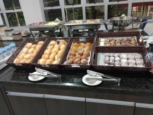 three trays of different types of donuts on a counter at Summit Inn Hotel Pouso Alegre in Pouso Alegre