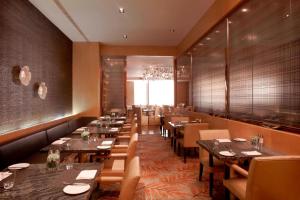 a dining room with tables and chairs and a chandelier at Guangzhou Marriott Hotel Tianhe in Guangzhou