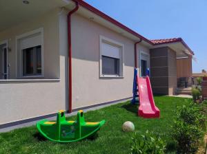 a yard with two play equipment in front of a house at A & F Apartments - Ari's house in Kalivia Poligirou