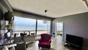 a living room with a pink chair and a view of the ocean at Ocean BreezeApartment: WakeUp 2 Sound of the Waves in Zandvoort
