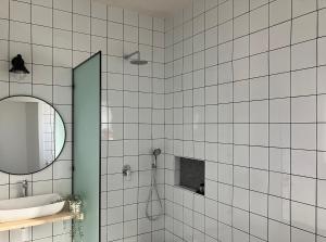 uma casa de banho em azulejos brancos com um lavatório e um espelho. em בסנדלים: חאן בוטיק בגולן em Ma'ale Gamla